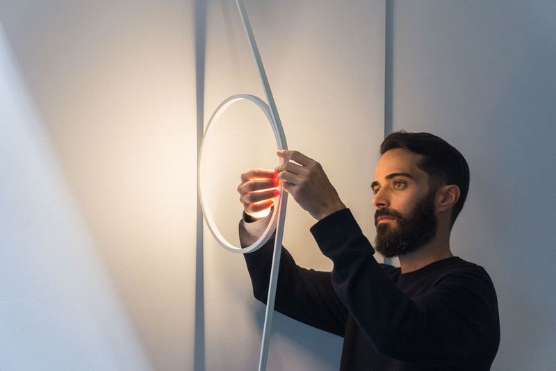 Wirering est une lumière sculpturale qui plane entre un mur et un lampadaire